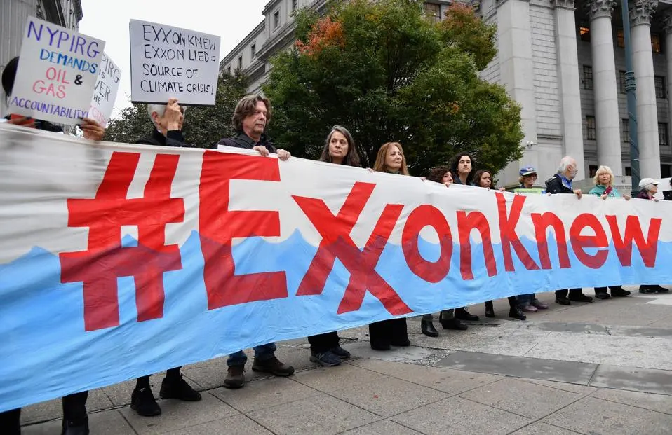 A dozen New Yorkers holding a banner that says "ExxonKnew" in bright red in front of a courthouse.